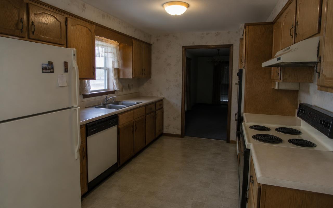 Dated oak kitchen remodeled with white cabinets, quartz counters and island — before